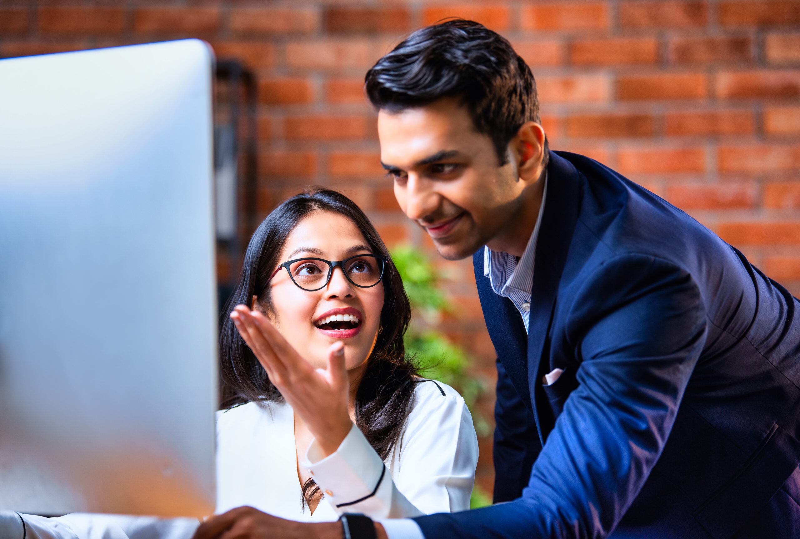 Indian business people using computer in office for project discussion, closeup of Asian corporate man and woman in professional attire collaborating on computer in cozy modern office interior